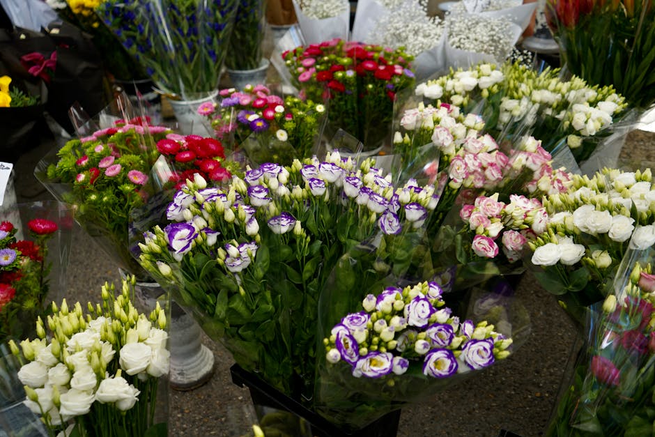 A variety of fresh floral bouquets displayed on a table, featuring lisianthus flowers in shades of purple, white, and pink, each wrapped in clear cellophane. The arrangements include lisianthus buds a
